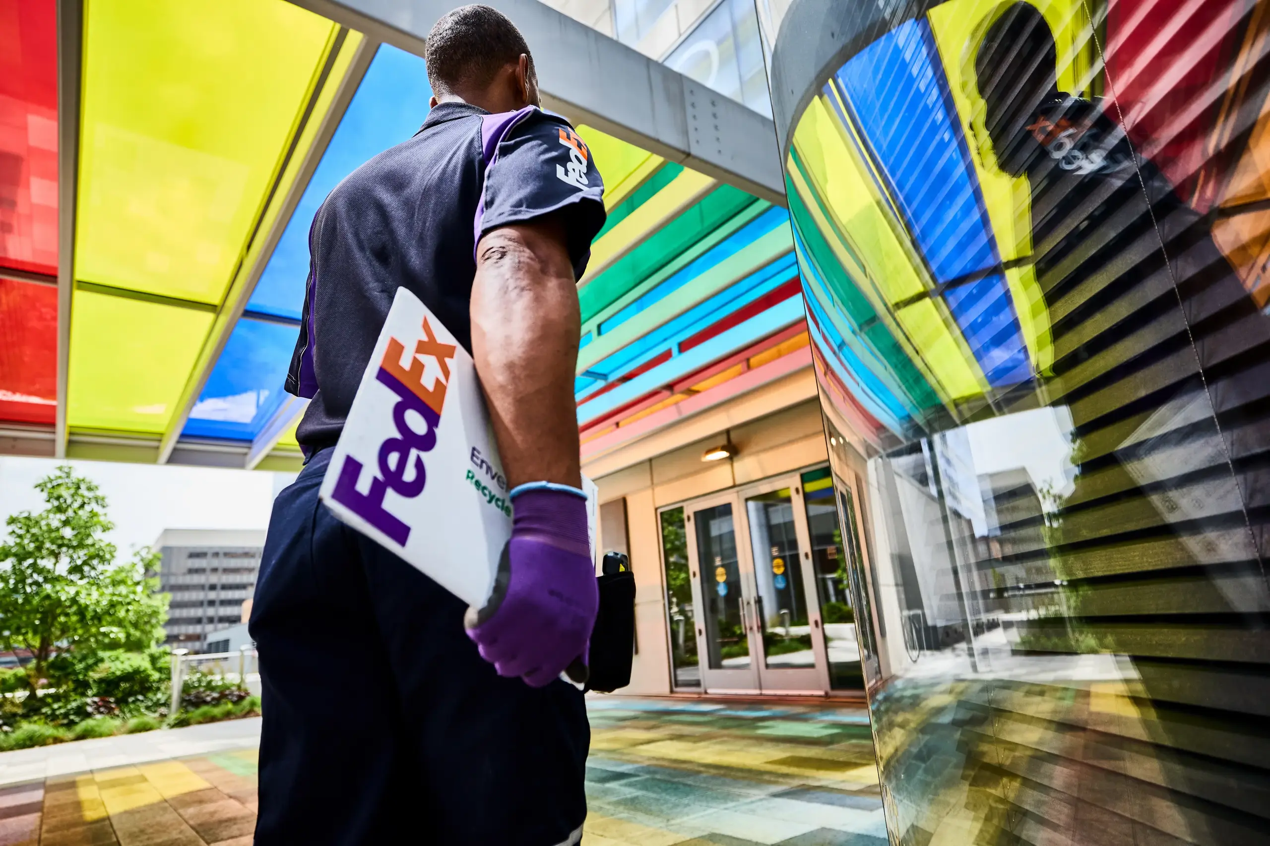 FedEx courier carrying a package under a colourful glass canopy