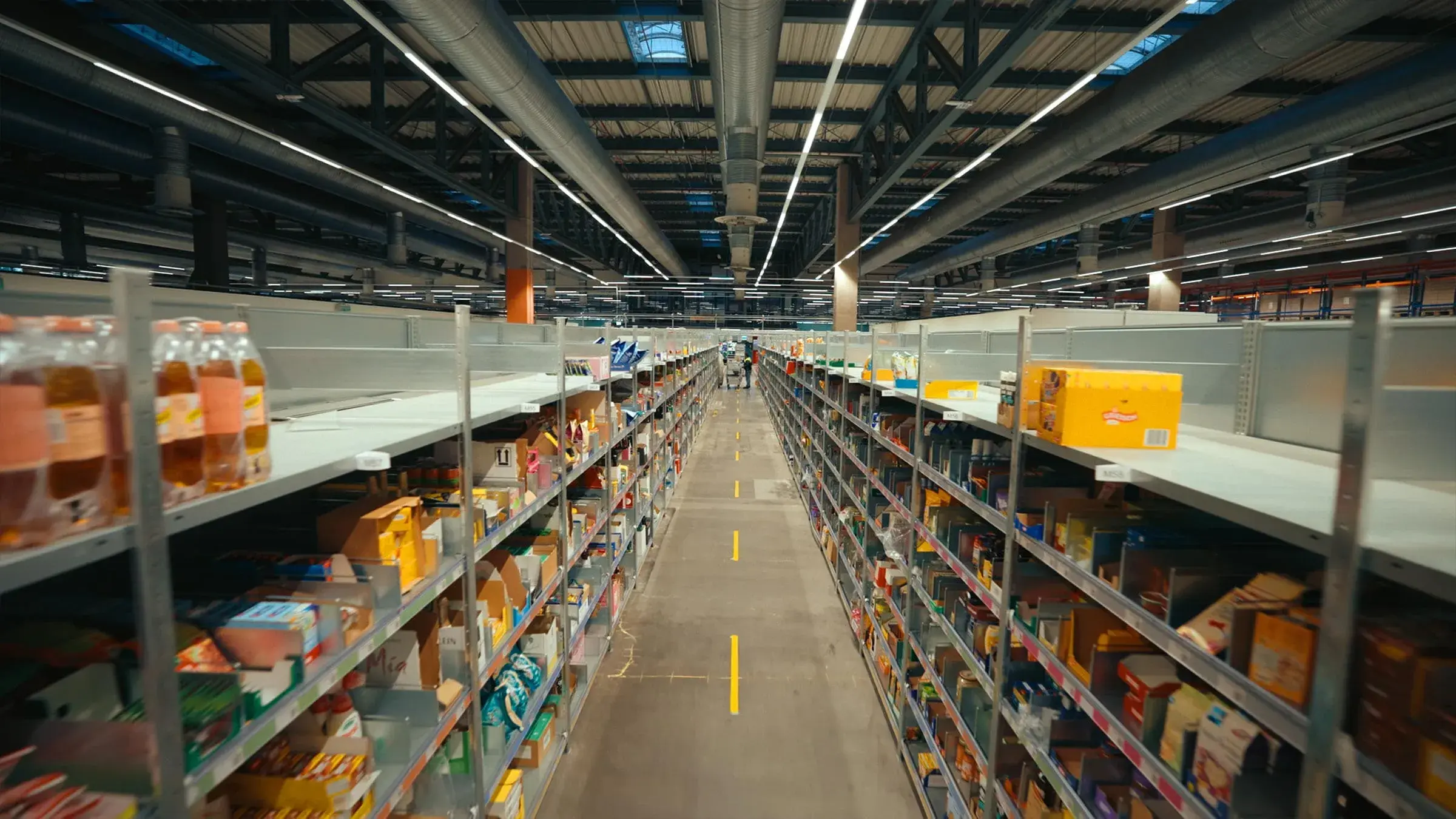 Long aisle of stocked shelves in a REWE warehouse
